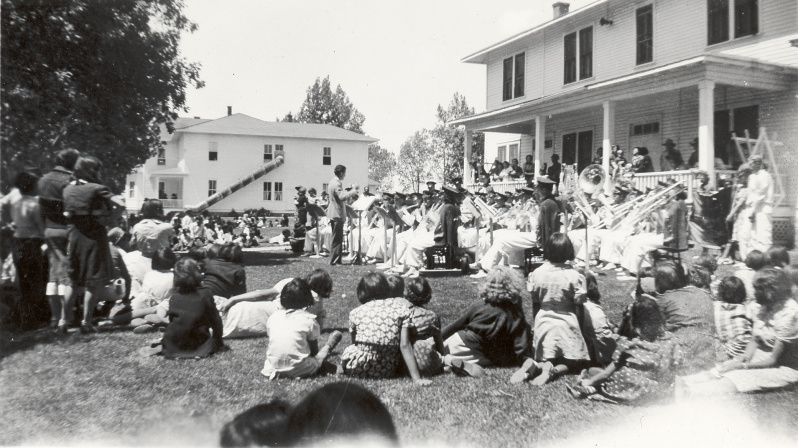 Historic image of a large group of students sitting on the grass
